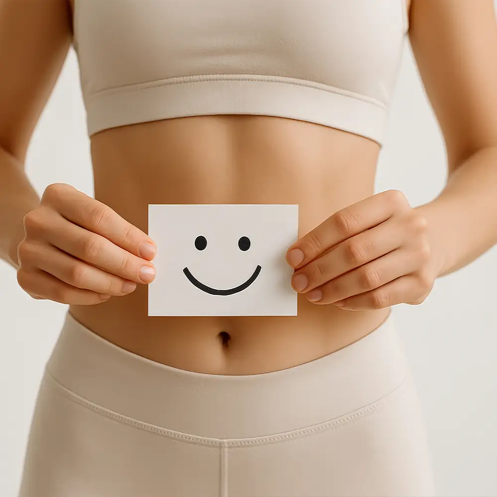 Athletische Frau hält Smiley-Karte über dem Bauch, steht für eine glückliche Darmgesundheit